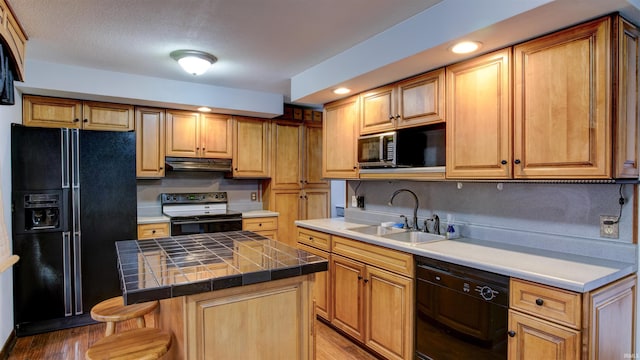 856 S Balthazar Dr, Santa Claus, IN 47579 - kitchen with black appliances, a sink, under cabinet range hood, wood finished floors, and a center island