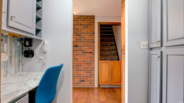 office area featuring brick wall and light wood-type flooring