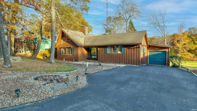 856 S Balthazar Dr, Santa Claus, IN 47579 - view of front of property featuring board and batten siding, driveway, an attached garage, a chimney, and roof with shingles