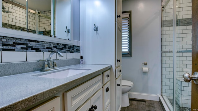 bathroom with a shower with door, tasteful backsplash, hardwood / wood-style floors, vanity, and toilet