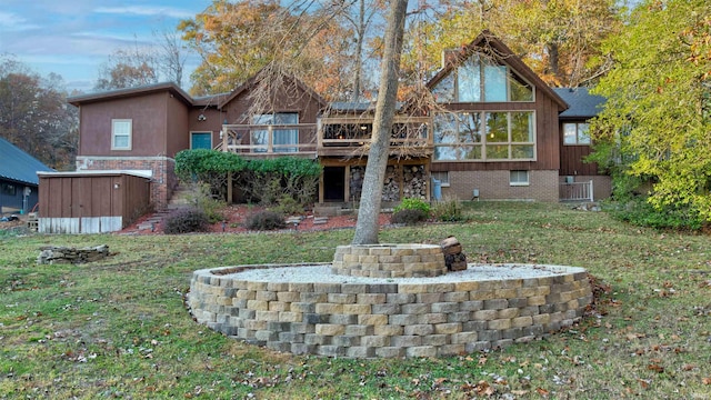 rear view of house featuring a deck, a lawn, a storage shed, and a fire pit