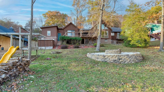 view of yard with a playground, a wooden deck, and a fire pit