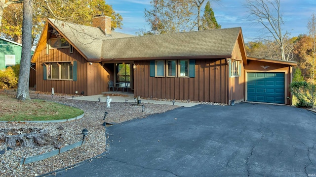 856 S Balthazar Dr, Santa Claus, IN 47579 - view of front of home featuring board and batten siding, a shingled roof, a chimney, a garage, and asphalt driveway