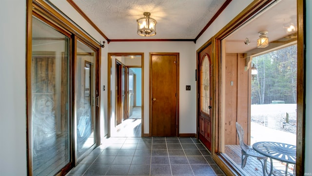 foyer entrance with a textured ceiling, a notable chandelier, and ornamental molding