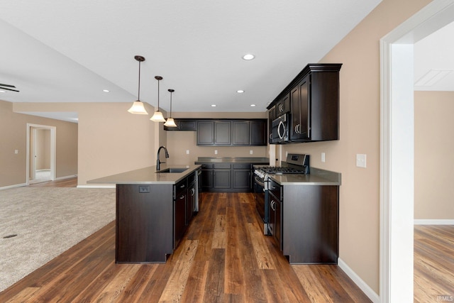 kitchen with appliances with stainless steel finishes, a sink, dark wood finished floors, and recessed lighting