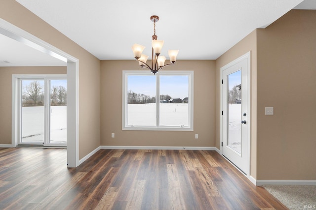 unfurnished dining area with a chandelier, dark wood-style floors, and baseboards