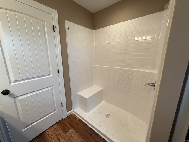 bathroom with wood-type flooring and a tile shower