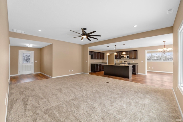 unfurnished living room with carpet, a chandelier, a sink, ceiling fan, and recessed lighting