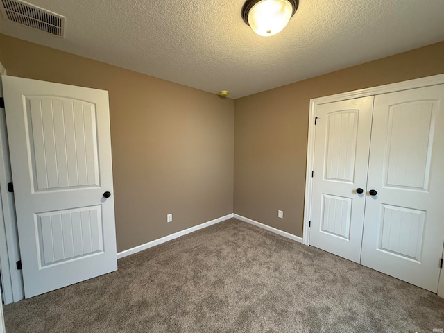 unfurnished bedroom featuring light colored carpet, a closet, and a textured ceiling