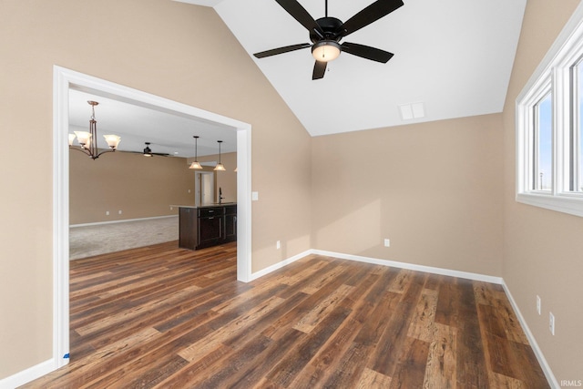 unfurnished living room with dark hardwood / wood-style flooring, ceiling fan with notable chandelier, and lofted ceiling