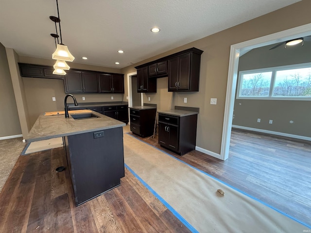 kitchen featuring hardwood / wood-style floors, decorative light fixtures, sink, and a center island with sink