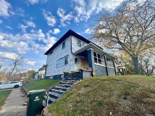 view of side of property featuring a lawn and covered porch