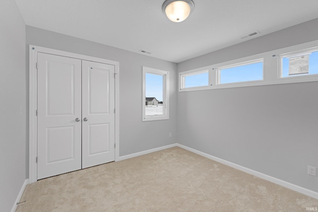 unfurnished bedroom with a closet and light carpet