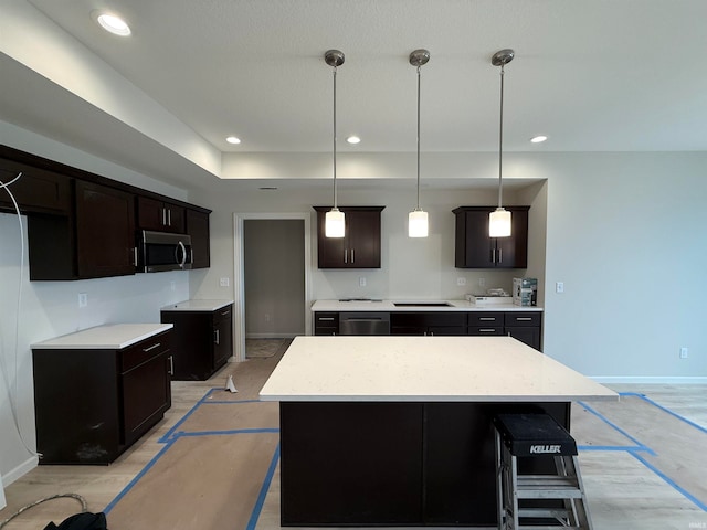 kitchen featuring stainless steel appliances, pendant lighting, a kitchen island, and dark brown cabinets