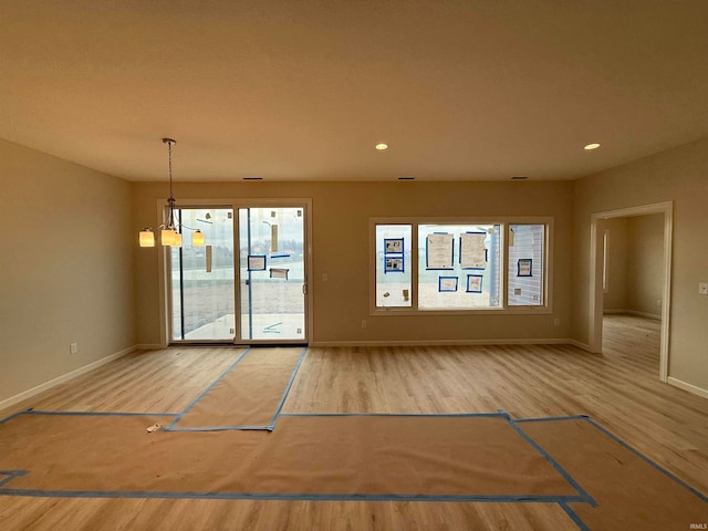 spare room featuring hardwood / wood-style floors and a chandelier