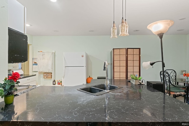 kitchen with white cabinetry, hanging light fixtures, sink, and white fridge