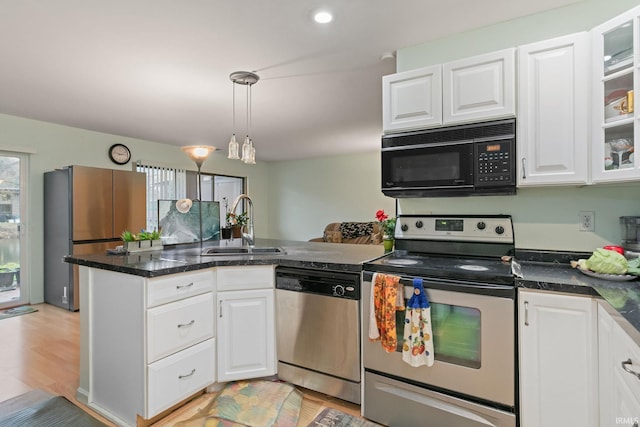 kitchen featuring white cabinets, light wood-type flooring, appliances with stainless steel finishes, and hanging light fixtures