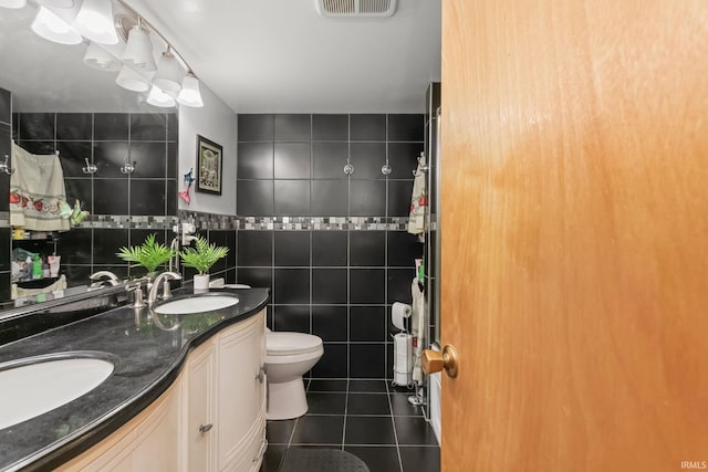 bathroom featuring tile patterned flooring, vanity, toilet, and tile walls