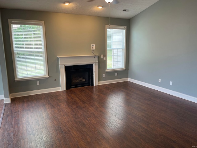 unfurnished living room with a textured ceiling, dark hardwood / wood-style flooring, and ceiling fan