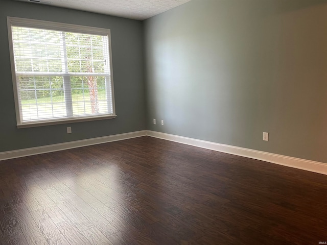 unfurnished room featuring dark hardwood / wood-style flooring and a textured ceiling