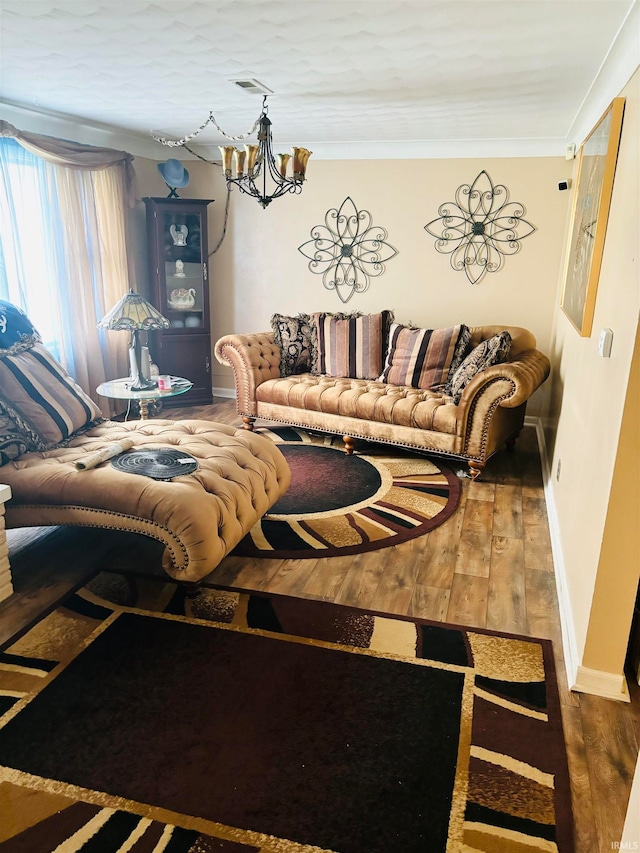 living room featuring ornamental molding, hardwood / wood-style floors, and an inviting chandelier