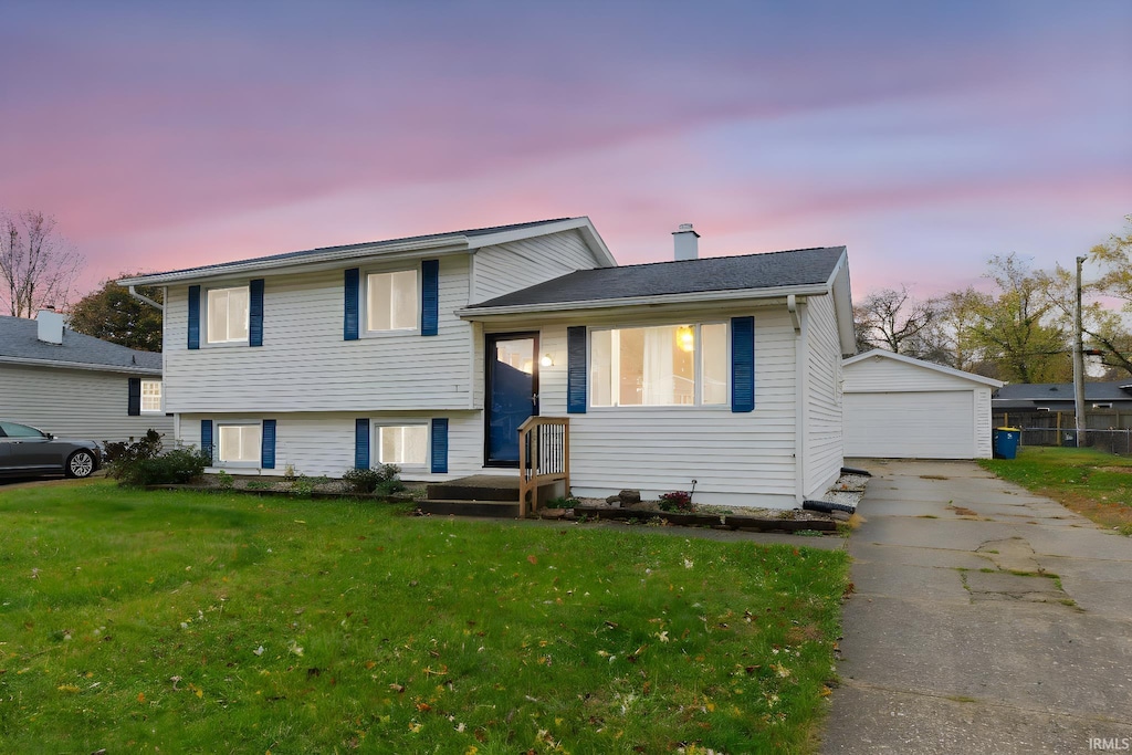 tri-level home featuring an outbuilding, a garage, and a yard