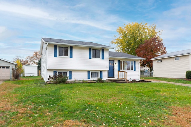 tri-level home with a front lawn, a garage, and an outbuilding