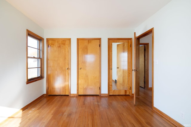 unfurnished bedroom featuring wood-type flooring and multiple closets