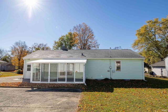 rear view of property with a sunroom and a yard