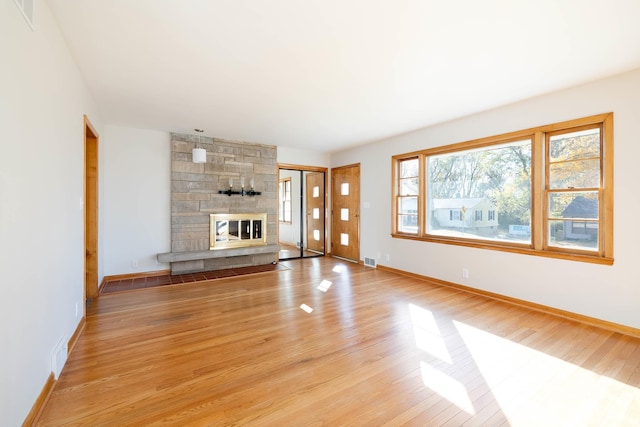 unfurnished living room with a stone fireplace and light hardwood / wood-style flooring