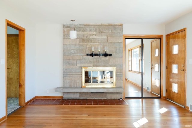 unfurnished living room with a stone fireplace and wood-type flooring