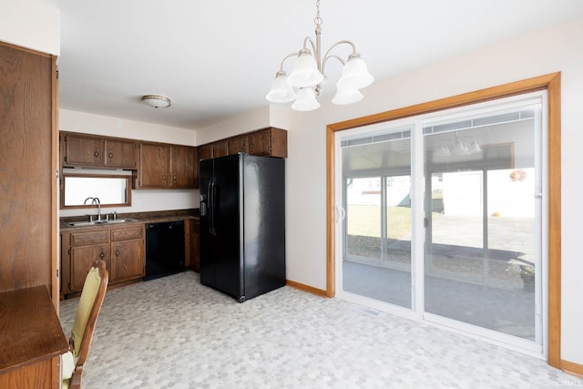 kitchen with hanging light fixtures, black appliances, sink, and a notable chandelier