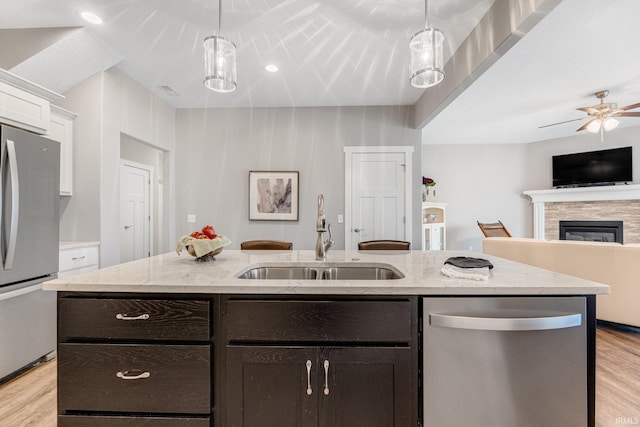 kitchen with light hardwood / wood-style floors, sink, appliances with stainless steel finishes, hanging light fixtures, and white cabinets