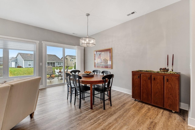 dining room with light wood-type flooring and a notable chandelier