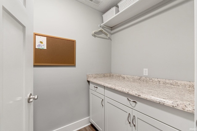 clothes washing area with wood-type flooring and a textured ceiling