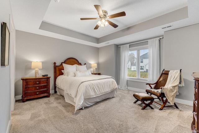 carpeted bedroom featuring ceiling fan and a raised ceiling