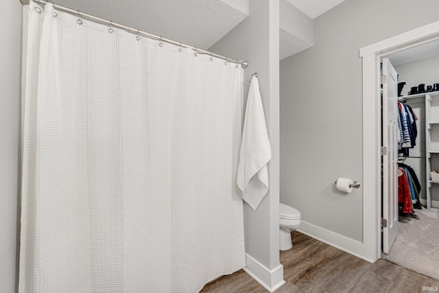 bathroom featuring wood-type flooring, a textured ceiling, and toilet