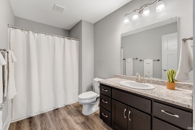 bathroom featuring walk in shower, a textured ceiling, wood-type flooring, vanity, and toilet