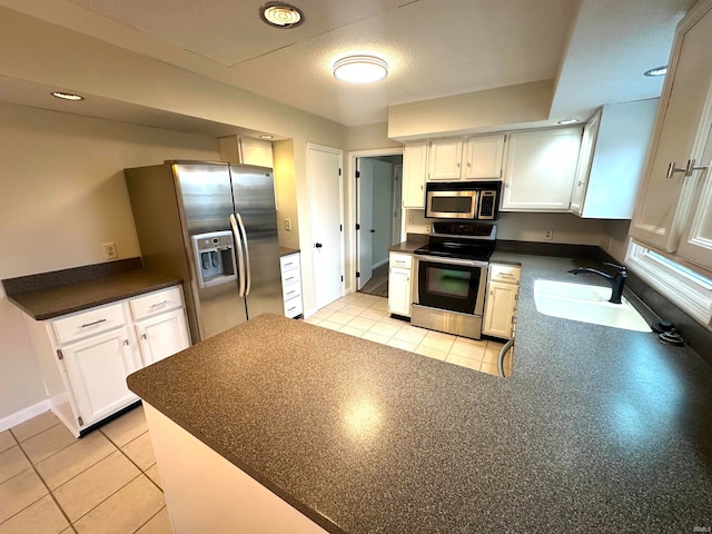 kitchen featuring appliances with stainless steel finishes, sink, light tile patterned floors, and white cabinets