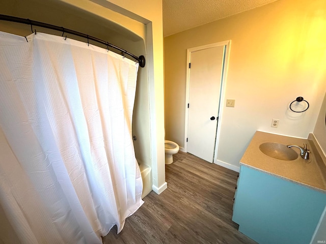 full bathroom featuring shower / bathtub combination with curtain, hardwood / wood-style floors, vanity, a textured ceiling, and toilet