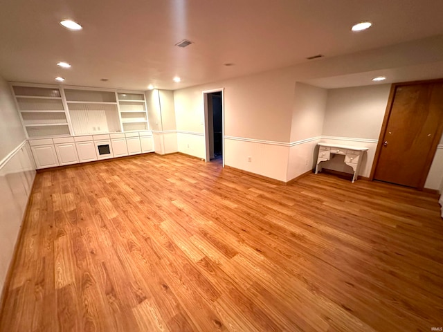 unfurnished living room featuring light hardwood / wood-style flooring and built in shelves