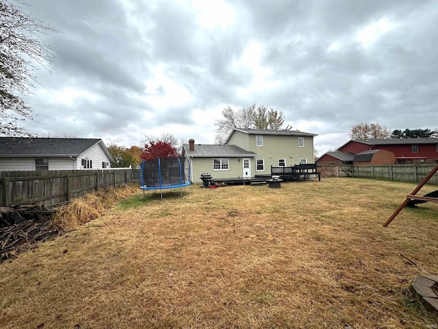 rear view of house featuring a yard, a deck, and a trampoline