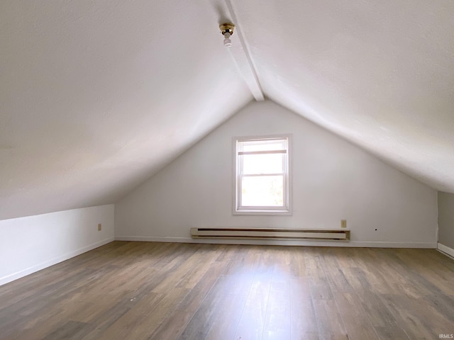 additional living space featuring a baseboard heating unit, wood-type flooring, and vaulted ceiling with beams