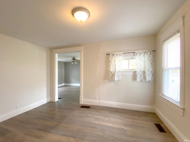 unfurnished room featuring a wealth of natural light, dark wood-type flooring, and ceiling fan