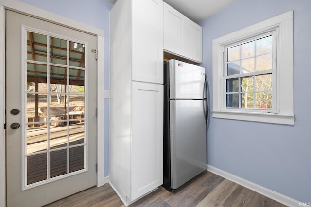 kitchen with white cabinets, hardwood / wood-style floors, and stainless steel fridge