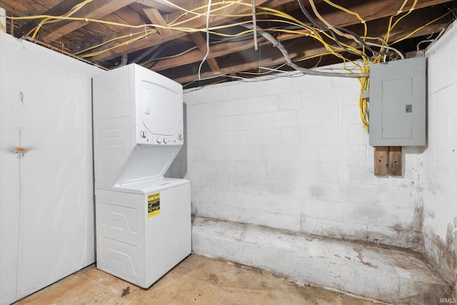 basement featuring stacked washer / drying machine and electric panel