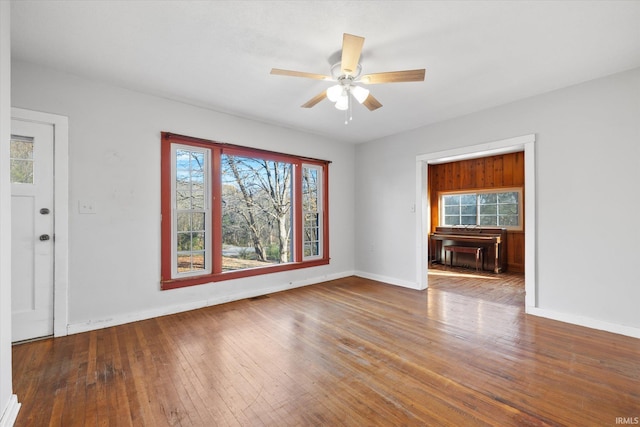 unfurnished living room featuring ceiling fan, a wealth of natural light, and wood-type flooring