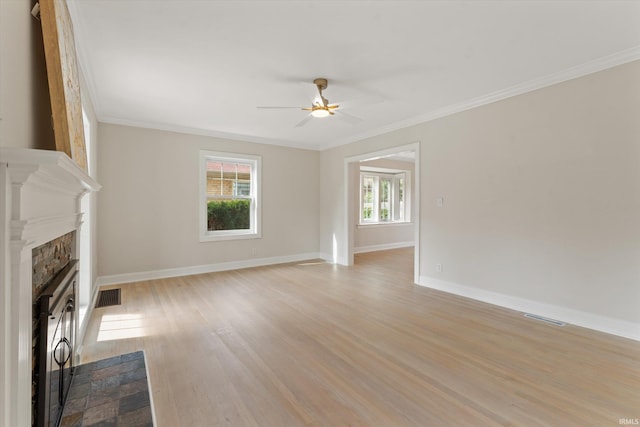 unfurnished living room with light wood-type flooring, a wealth of natural light, ornamental molding, and a fireplace