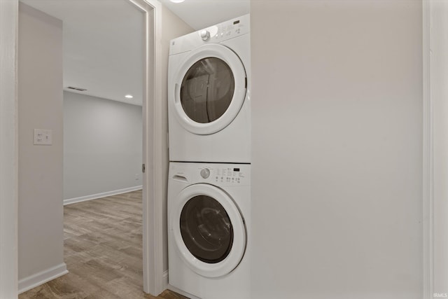 laundry area featuring stacked washer and clothes dryer and light hardwood / wood-style floors