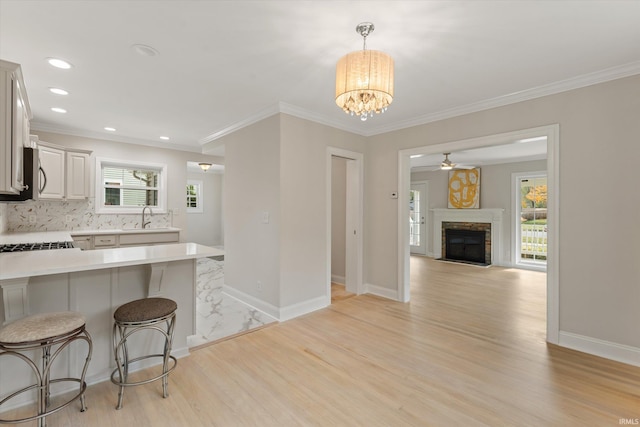 kitchen featuring pendant lighting, decorative backsplash, sink, light hardwood / wood-style floors, and a kitchen breakfast bar